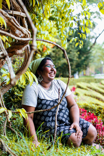 dark skinned Indian non-binary individual smiling in park photo