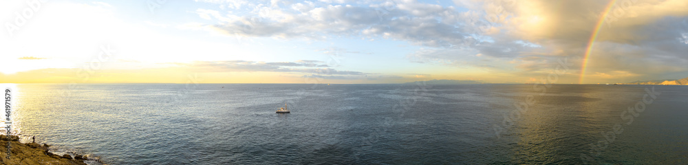 Panorama. Morning seascape after the rain. Clouds and rainbow over the water. Fishboat in the sea. Panorama. Morning seascape after the rain. Clouds and rainbow over the water. Fishboat in the sea.