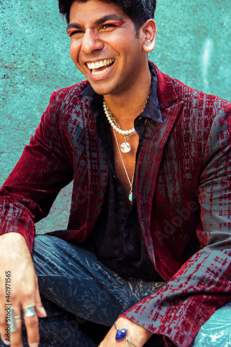 fashion portrait of dark skinned Indian man in concrete surroundings, laughing photo