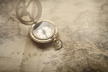 Retro style antique golden compass (sundial) and old nautical chart close-up. Vintage still life. Sailing accessories. Wanderlust, travel and navigation theme. Graphic resources, copy space