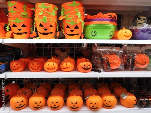 Plastic Halloween pumpkins and felt Halloween buckets on store shelves, along with other items such as a plastic skull or spider web.