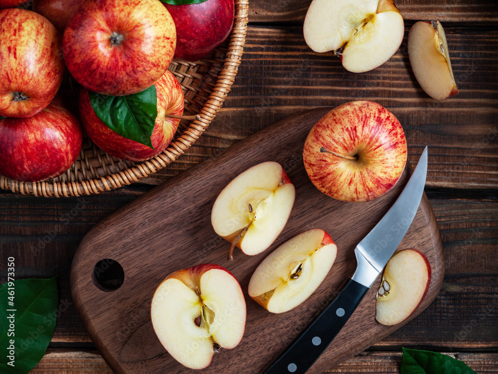Sliced ​​fresh apples on a wooden cutting board next to a fruit knife on a wooden table. View from above. Horizontal. flat lay.