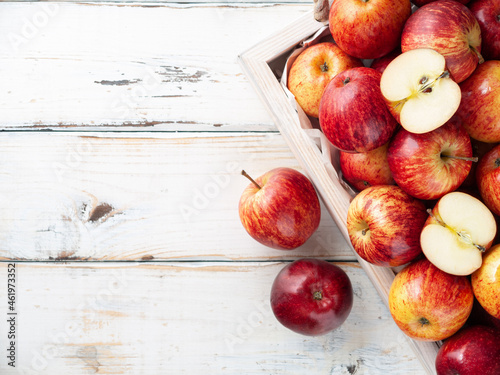 Fresh organic apples in wooden box on the white wooden background with sliced apple in the top. Top view. Copy space, Horizontal. New Zealand gala variety.