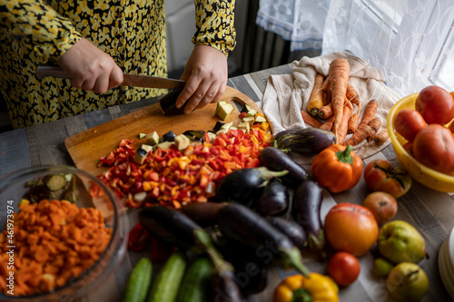 woman in yellow dress prepares vegetables for pickling and wields knife