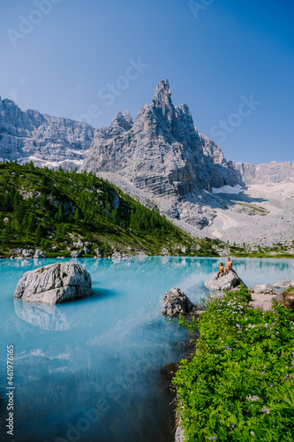 Lake Sorapis Italian Dolomites, Morning with clear sky on Lago di Sorapis in Italian Dolomites, lake with unique turquoise color water in Belluno province in Nothern Italy. couple in the mountains photo