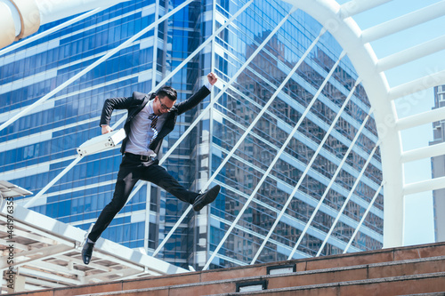Successful businessman celebrating his victory with jump up in feeling happy on cityscape background.