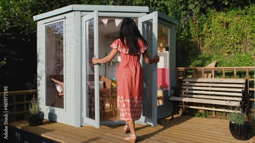 A young asian women opening the doors and entering a garden summer house