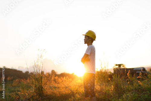 Young man wearing safety helmet standing over sunset metaphor new generation and environment conservation, Climate Change Solution concept. photo