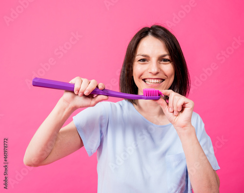 Beautiful happy young woman with big toothbrush on blank pink background