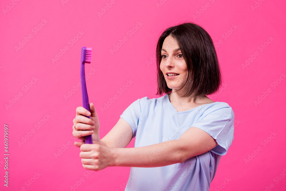 Beautiful happy young woman with big toothbrush on blank pink background Beautiful happy young woman with big toothbrush on blank pink background