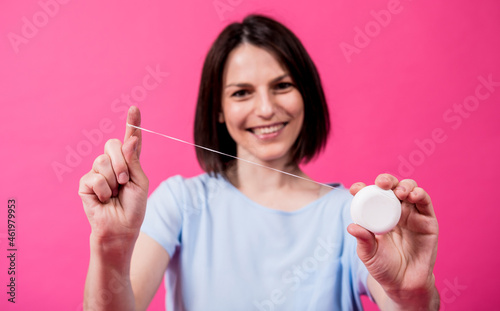 Beautiful young woman use dental floss on pink background