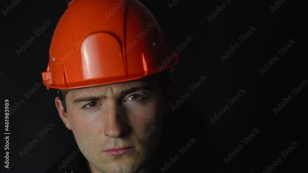 man in orange construction helmet on black background man in orange construction helmet on black background