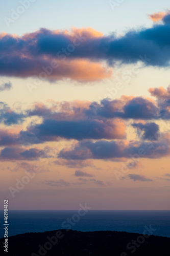 Stunning seascape with some fluffy clouds on an orange sky during a beautiful sunrise. Sardinia, Italy.