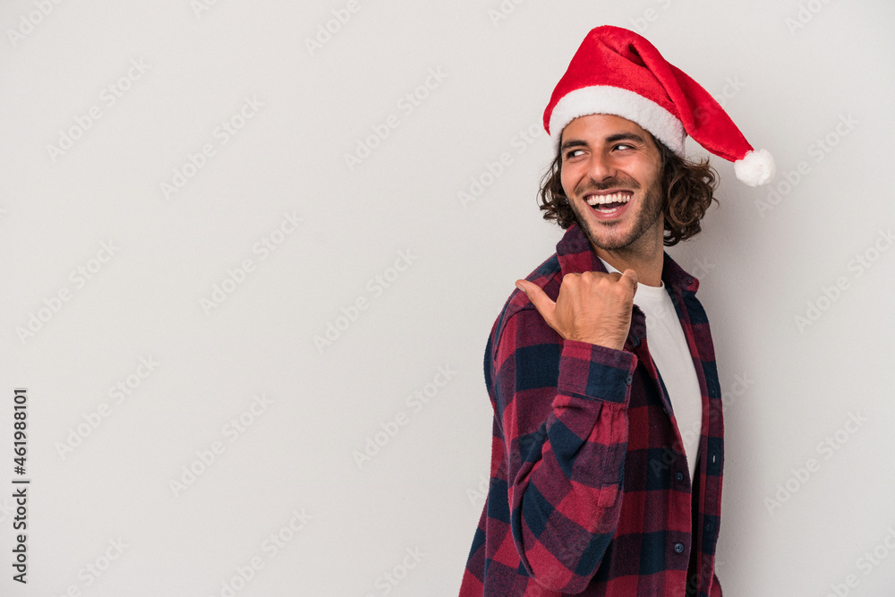 Young caucasian man celebrating Christmas isolated on gray background points with thumb finger away, laughing and carefree. Young caucasian man celebrating Christmas isolated on gray background points with thumb finger away, laughing and carefree.