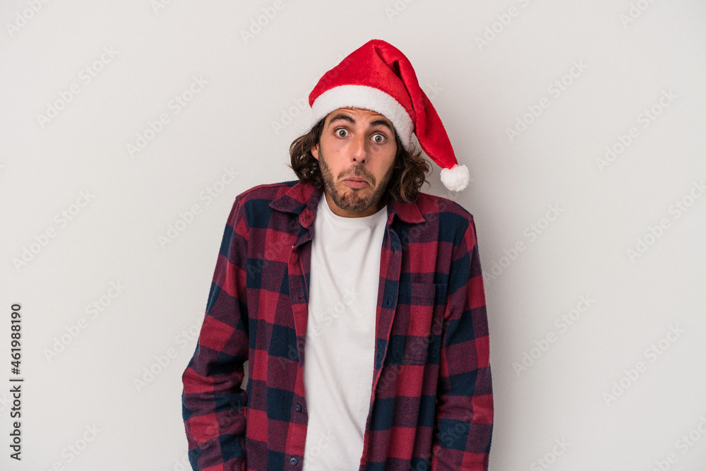 Young caucasian man celebrating Christmas isolated on gray background shrugs shoulders and open eyes confused. Young caucasian man celebrating Christmas isolated on gray background shrugs shoulders and open eyes confused.