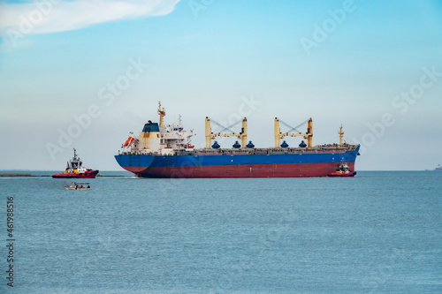 Tableau sur toile A cargo ship leaving the port with a guide