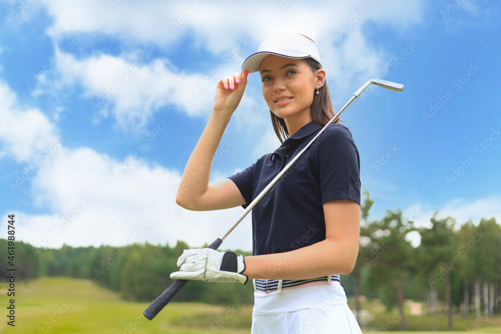 Professional female golfer holding golf club on field and looking away. Young woman standing on golf course on a sunny day. Professional female golfer holding golf club on field and looking away. Young woman standing on golf course on a sunny day.