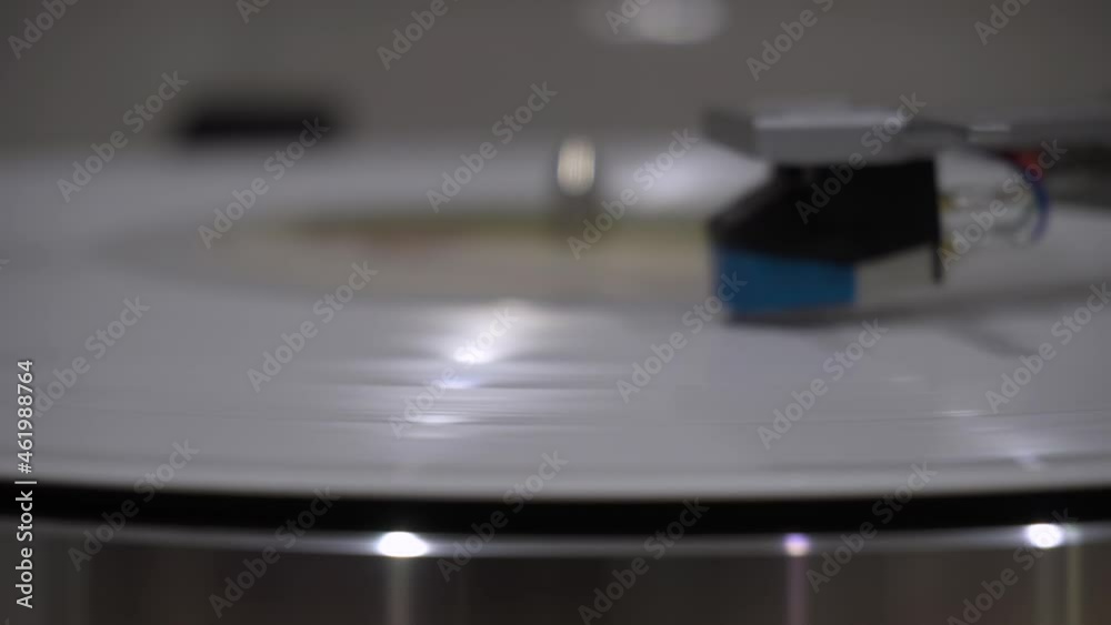 bright new white music vinyl record plays smoothly on the device. the needle slides over it. close-up.yellow lamp light bright new white music vinyl record plays smoothly on the device. the needle slides over it. close-up.yellow lamp light