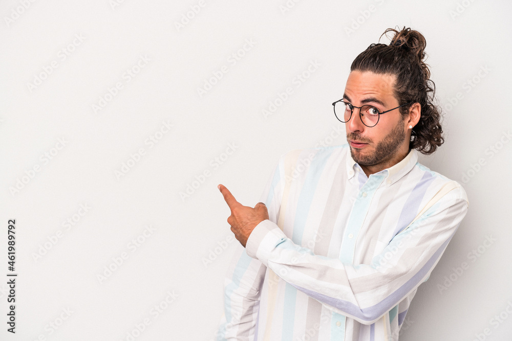 Young caucasian man isolated on gray background smiling and pointing aside, showing something at blank space. Young caucasian man isolated on gray background smiling and pointing aside, showing something at blank space.