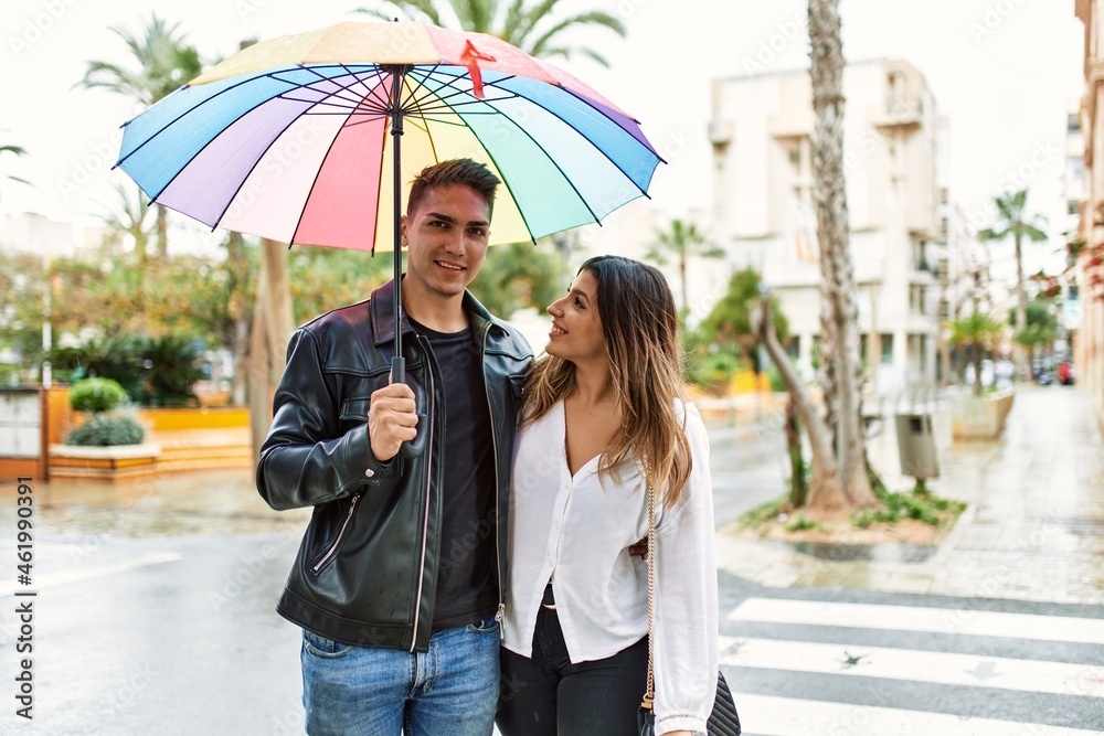 Fototapeta premium Young couple smiling happy holding umbrella standing at the city.