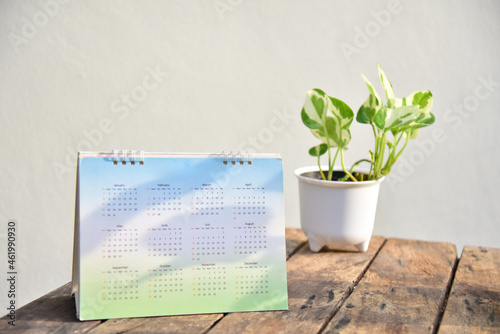 White calendar with plants on wood table.