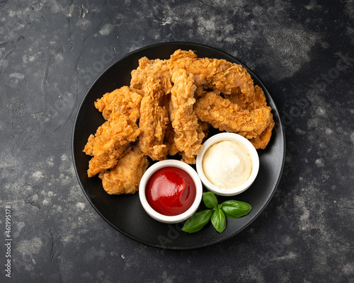 фотографія Fried Chicken strips with ketchup and mayonnaise on black plate
