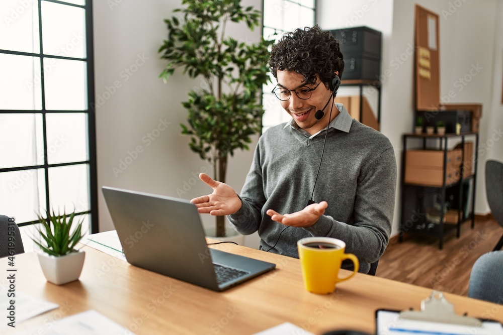 Young hispanic call center agent man having video call at the office.
