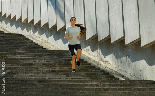 Asian woman in tracksuit runs down large stone stairs