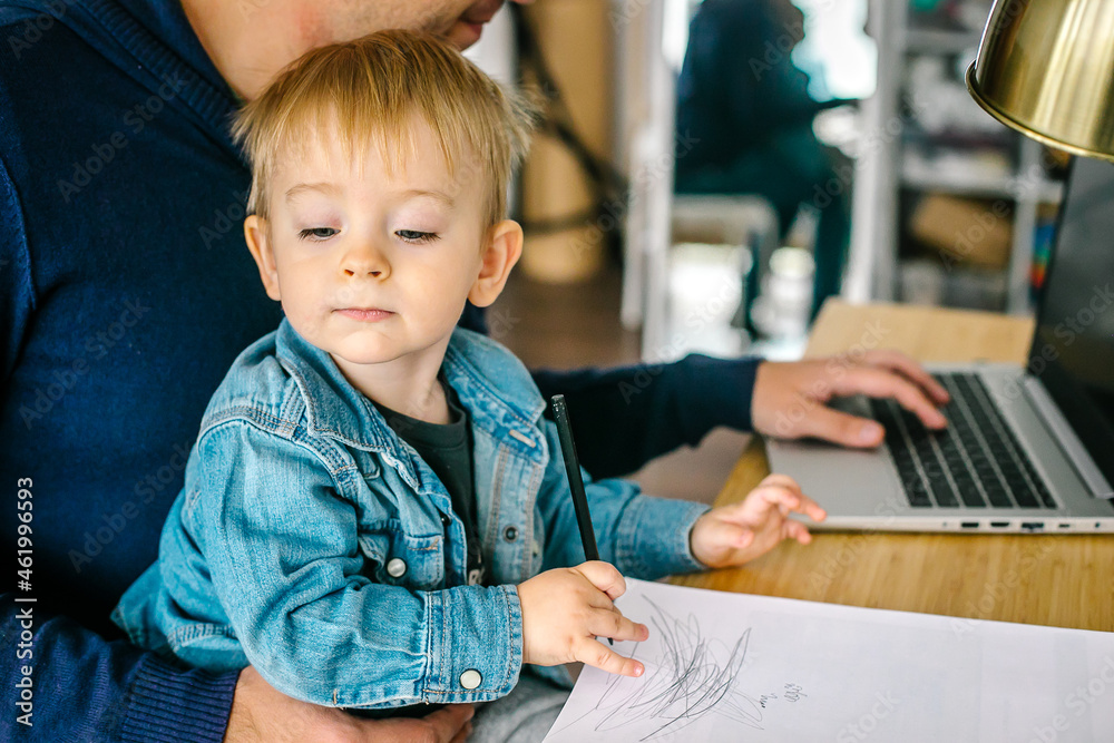 Father holding little baby son and working on laptop at home. Concept of remotely work. Father holding little baby son and working on laptop at home. Concept of remotely work.