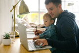 Father freelancer or business man with baby boy at desk at home office. Working from home