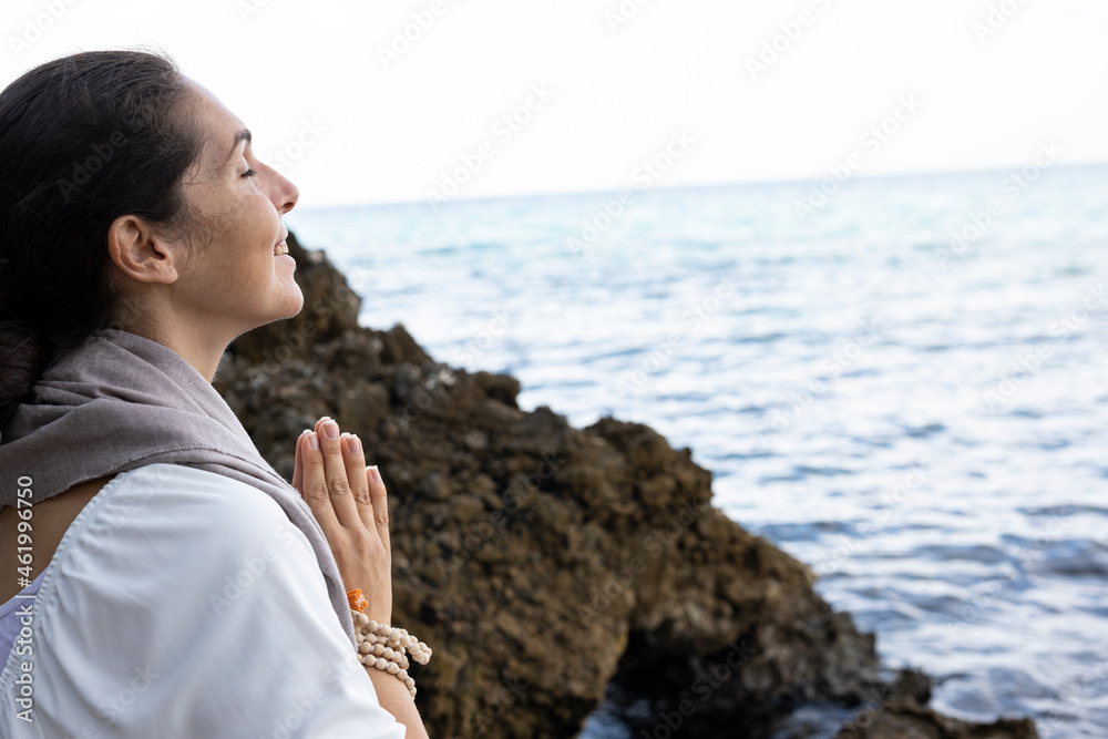 A beautiful pregnant young woman is meditating on the beach	