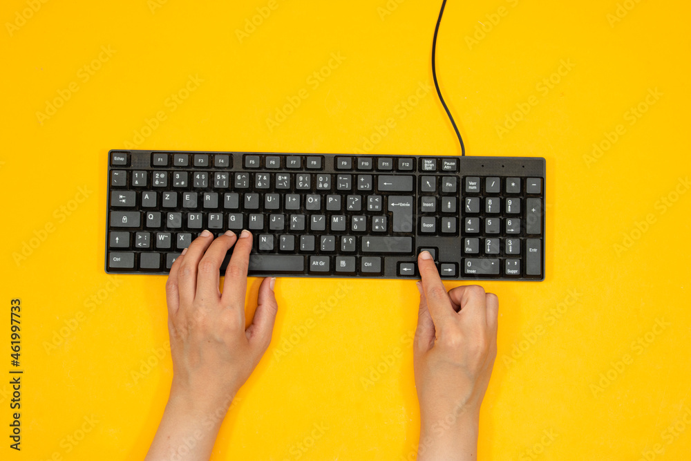 Woman using computer keyboard at yellow table with space for text Woman using computer keyboard at yellow table with space for text