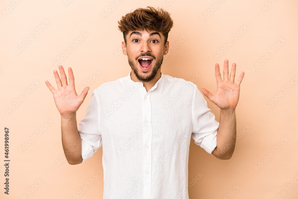 Fototapeta premium Young arab man isolated on beige background receiving a pleasant surprise, excited and raising hands.
