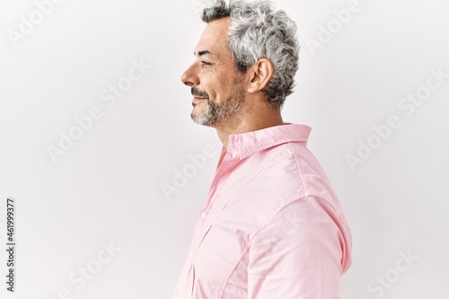 Middle age hispanic man standing over isolated background looking to side, relax profile pose with natural face with confident smile.