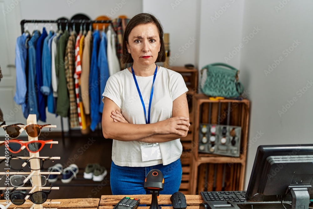 Beautiful middle age hispanic woman working as manager at retail boutique skeptic and nervous, disapproving expression on face with crossed arms. negative person.