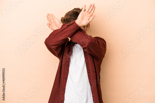 Young arab man isolated on beige background keeping two arms crossed, denial concept.
