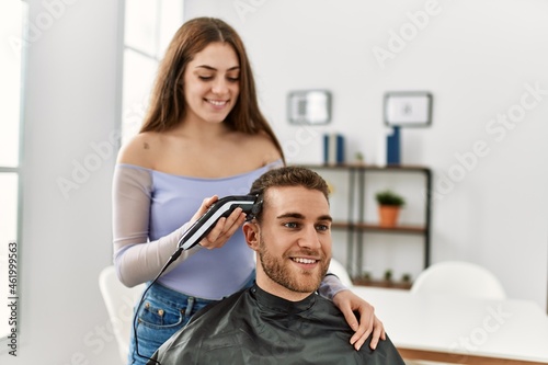 Young woman cutting hair her boyfriend at home.