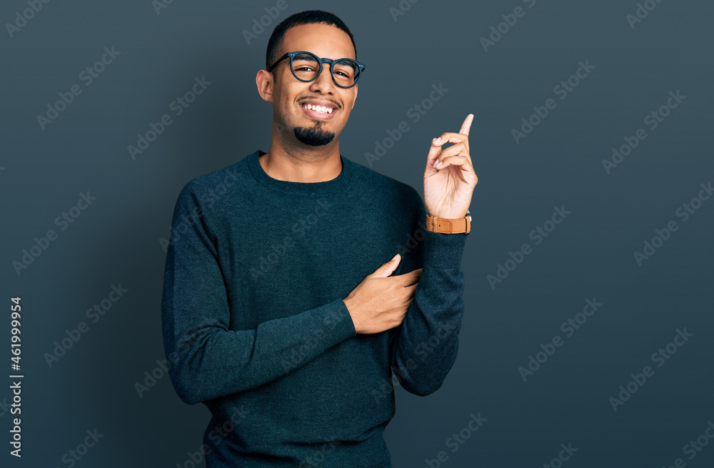 Young african american man wearing casual clothes and glasses with a big smile on face, pointing with hand and finger to the side looking at the camera. Young african american man wearing casual clothes and glasses with a big smile on face, pointing with hand and finger to the side looking at the camera.
