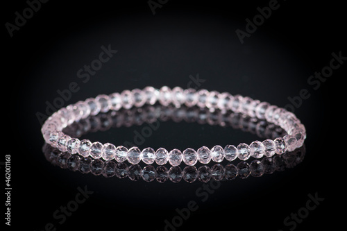 Bracelets natural stones in gentle pink colors, isolated on black reflective background. Selected focus.