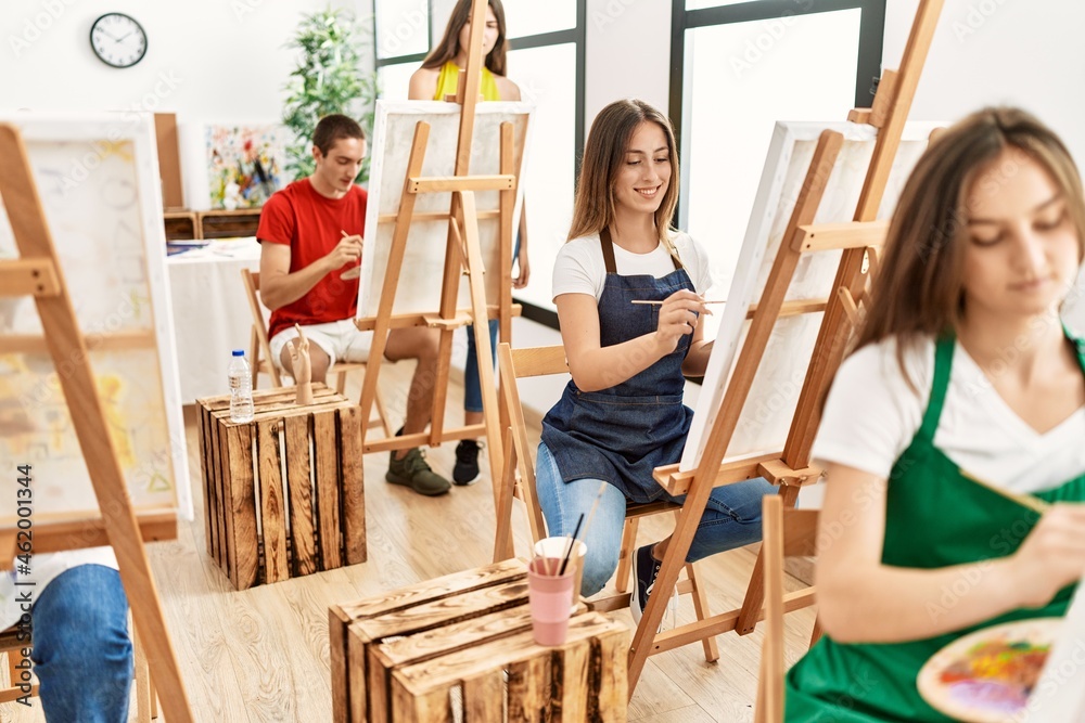 Young woman smiling happy drawing with group of people at art studio.
