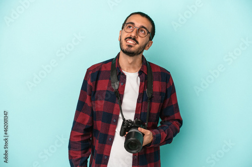 Young caucasian photographer man isolated on blue background dreaming of achieving goals and purposes