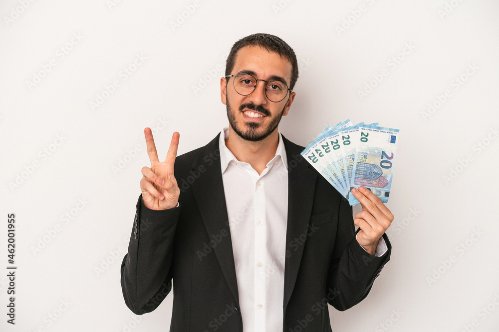 Young caucasian business man holding banknotes isolated on white background showing number two with fingers. Young caucasian business man holding banknotes isolated on white background showing number two with fingers.