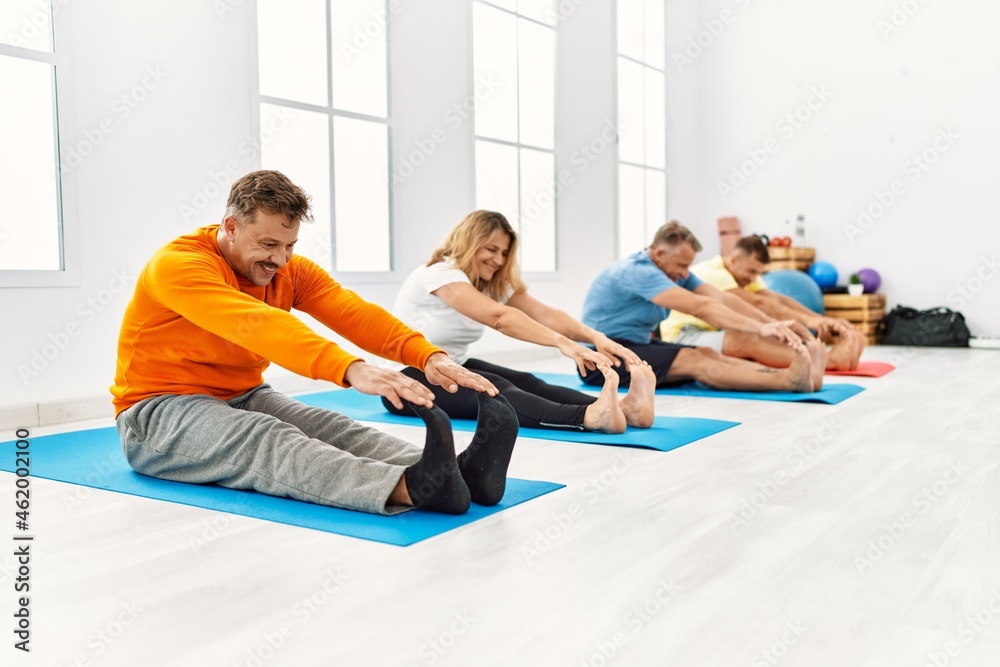 Group of middle age people training yoga at sport center. Group of middle age people training yoga at sport center.