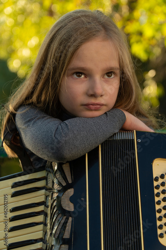 girl playing the accordion in the autumn park. autumn accordion. girl doing music. child in the autumn park