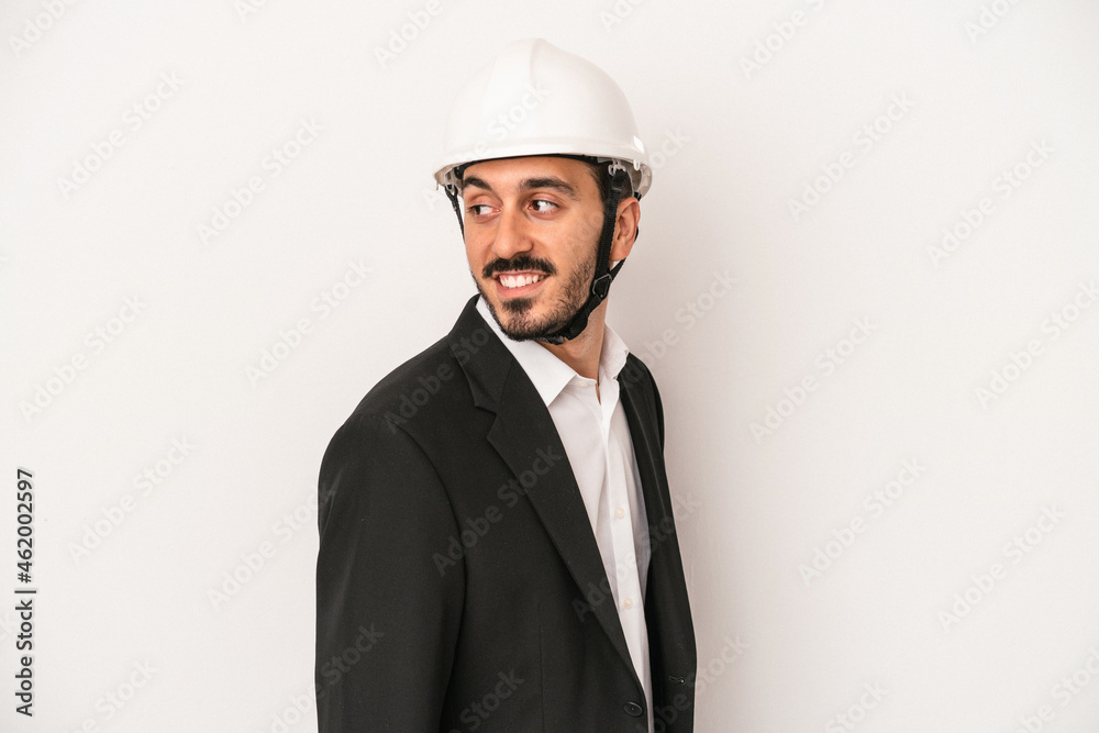 Young architect man wearing a construction helmet isolated on white background looks aside smiling, cheerful and pleasant. Young architect man wearing a construction helmet isolated on white background looks aside smiling, cheerful and pleasant.