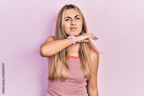 Beautiful hispanic woman wearing casual summer t shirt cutting throat with hand as knife, threaten aggression with furious violence