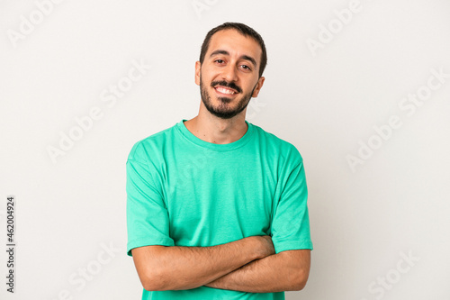 Young caucasian man isolated on white background who feels confident, crossing arms with determination.