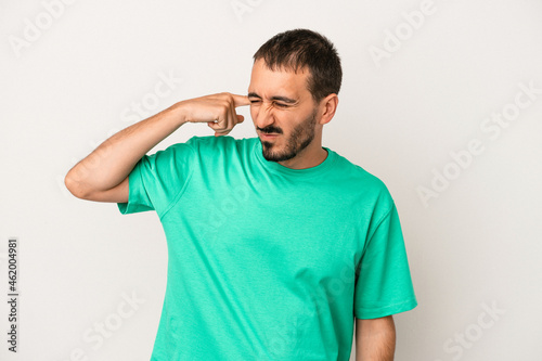 Young caucasian man isolated on white background covering ears with hands. © Asier