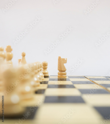 One person arranges white chess pieces on a wooden board. Brain-developing games