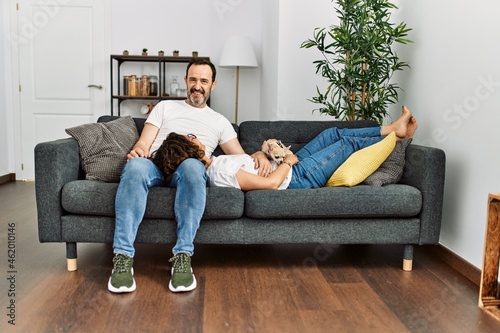 Middle age hispanic couple relaxed sitting on the sofa with dog at home. © Krakenimages.com